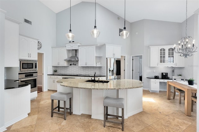 718 Glen Eagle Dr, Winter Springs, FL 32708 - kitchen with appliances with stainless steel finishes, wall chimney range hood, a sink, high vaulted ceiling, and a breakfast bar area
