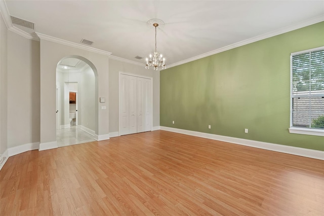 1542 Islay Ct, Apopka, FL 32712 - empty room with arched walkways, light wood-type flooring, a chandelier, crown molding, and baseboards