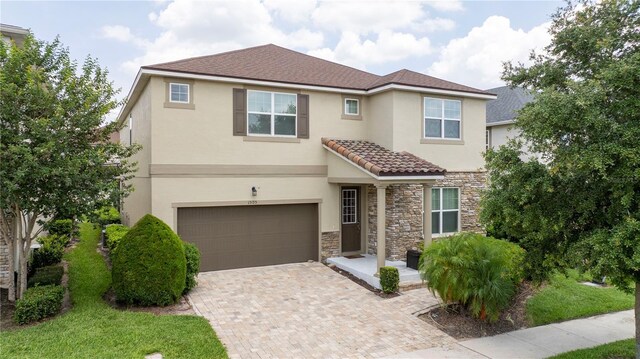 1505 Nassau Point Trl, Kissimmee, FL 34747 - view of property featuring stucco siding, a garage, stone siding, decorative driveway, and a tiled roof