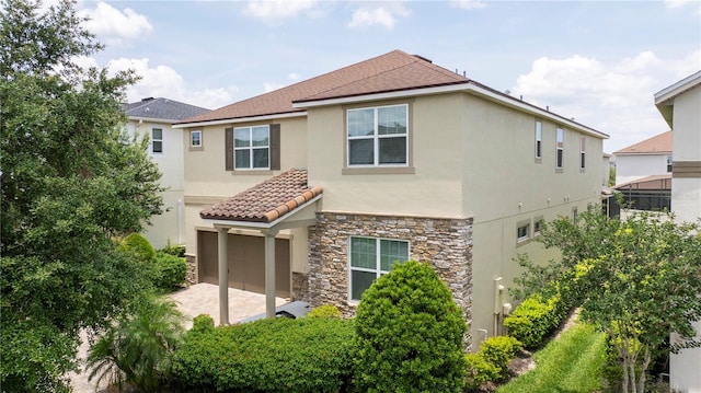 1505 Nassau Point Trl, Kissimmee, FL 34747 - rear view of house featuring stucco siding, stone siding, and a garage
