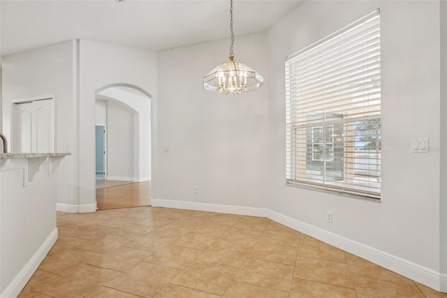 604 Cheviot Ct, Apopka, FL 32712 - unfurnished dining area featuring arched walkways, a chandelier, light tile patterned floors, and baseboards