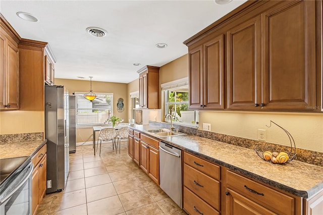 676 Dunblane Dr, Winter Park, FL 32792 - kitchen with stainless steel appliances, a sink, brown cabinetry, and plenty of natural light