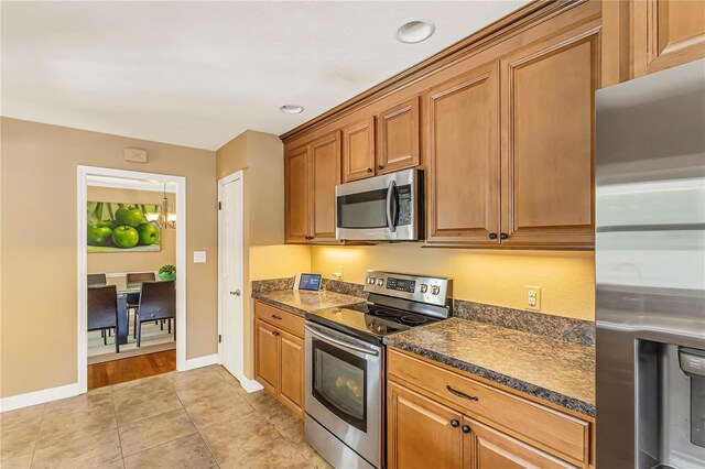 676 Dunblane Dr, Winter Park, FL 32792 - kitchen featuring appliances with stainless steel finishes, dark countertops, brown cabinets, light tile patterned floors, and baseboards