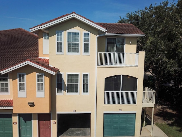 12106 Poppy Field Ln Unit 107, Orlando, FL 32837 - view of front of house with a balcony, a tiled roof, an attached garage, stucco siding, and driveway