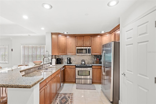 7650 Whisper Way Unit 104, Reunion, FL 34747 - kitchen with appliances with stainless steel finishes, a sink, a peninsula, light stone countertops, and decorative backsplash