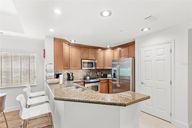 7650 Whisper Way Unit 104, Reunion, FL 34747 - kitchen featuring stainless steel appliances, light stone countertops, a peninsula, a sink, and baseboards