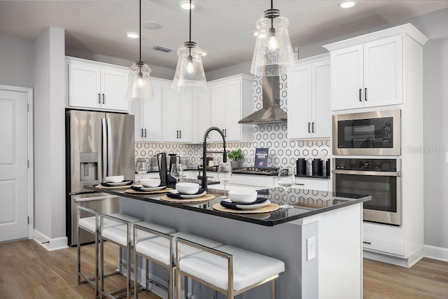 1341 Lumpini St, Saint Cloud, FL 34771 - kitchen featuring appliances with stainless steel finishes, wall chimney exhaust hood, dark countertops, a kitchen breakfast bar, and recessed lighting