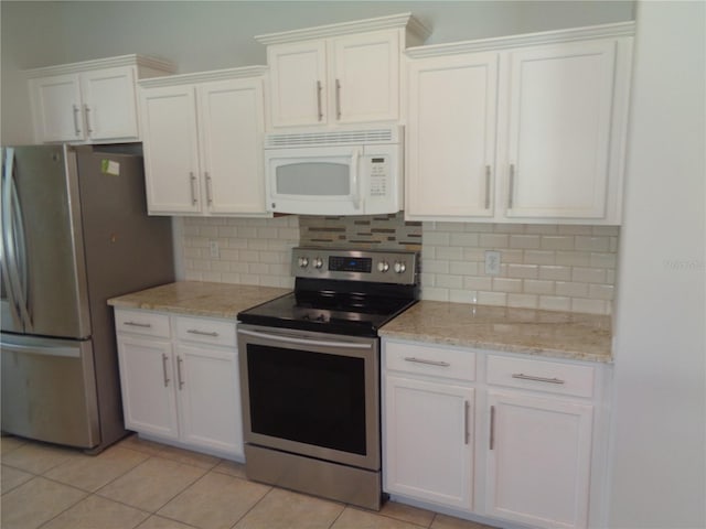2451 Strandhill St, Orlando, FL 32824 - kitchen with stainless steel appliances, white cabinetry, backsplash, light stone countertops, and light tile patterned flooring