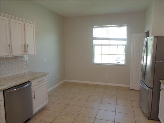 2451 Strandhill St, Orlando, FL 32824 - kitchen featuring stainless steel appliances, white cabinets, backsplash, light tile patterned floors, and baseboards