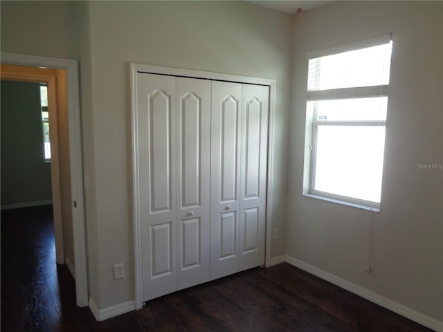 2451 Strandhill St, Orlando, FL 32824 - unfurnished bedroom featuring multiple windows, dark wood-type flooring, and a closet