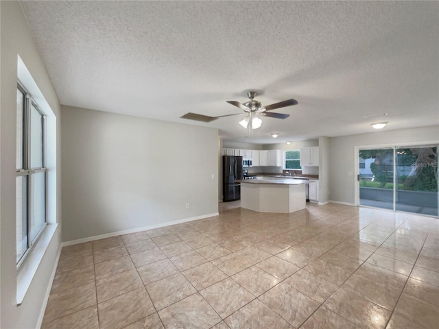 9514 SE 168th Maplesong Ln, The Villages, FL 32162 - kitchen featuring freestanding refrigerator, light tile patterned floors, white cabinetry, open floor plan, and a textured ceiling