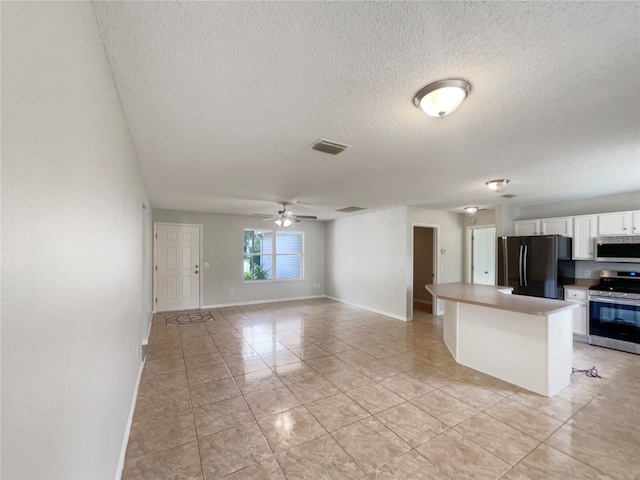 9514 SE 168th Maplesong Ln, The Villages, FL 32162 - kitchen with stainless steel appliances, white cabinets, light tile patterned floors, a textured ceiling, and ceiling fan