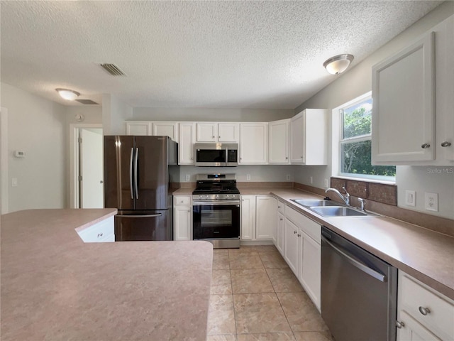 9514 SE 168th Maplesong Ln, The Villages, FL 32162 - kitchen featuring appliances with stainless steel finishes, a sink, a textured ceiling, white cabinets, and light countertops