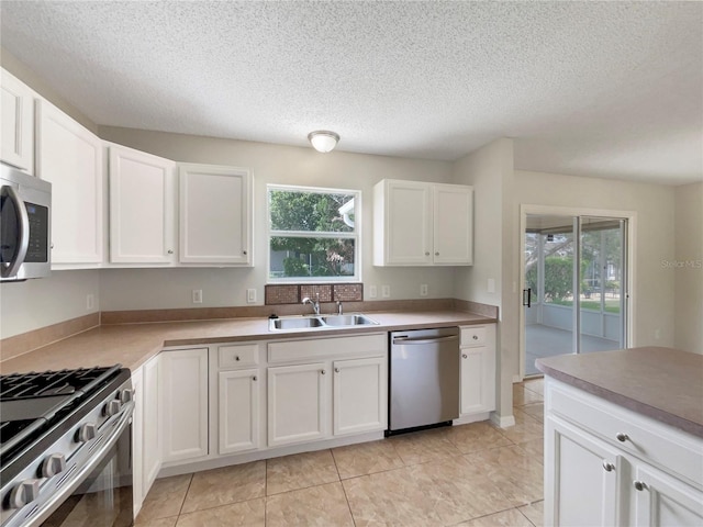 9514 SE 168th Maplesong Ln, The Villages, FL 32162 - kitchen featuring appliances with stainless steel finishes, a sink, healthy amount of natural light, white cabinetry, and a textured ceiling