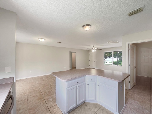 9514 SE 168th Maplesong Ln, The Villages, FL 32162 - kitchen with open floor plan, white cabinetry, a ceiling fan, a center island, and a textured ceiling