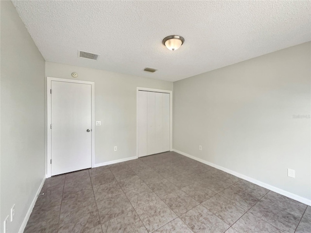 9514 SE 168th Maplesong Ln, The Villages, FL 32162 - unfurnished bedroom with a textured ceiling, a closet, tile patterned flooring, and baseboards