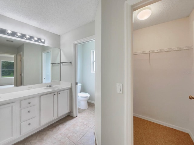 9514 SE 168th Maplesong Ln, The Villages, FL 32162 - bathroom with a textured ceiling, vanity, toilet, a walk in closet, and baseboards