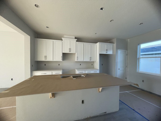 1356 Lumpini St, Saint Cloud, FL 34771 - kitchen featuring a kitchen island, white cabinets, a kitchen breakfast bar, and a textured ceiling