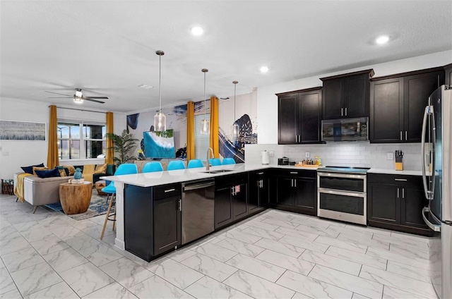 4161 Paragraph Dr, Kissimmee, FL 34746 - kitchen with stainless steel appliances, a peninsula, a sink, open floor plan, and light marble finish flooring