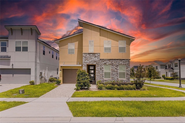1809 Tropical Palms Cir, Kissimmee, FL 34747 - contemporary house featuring stone siding, stucco siding, an attached garage, decorative driveway, and a front lawn