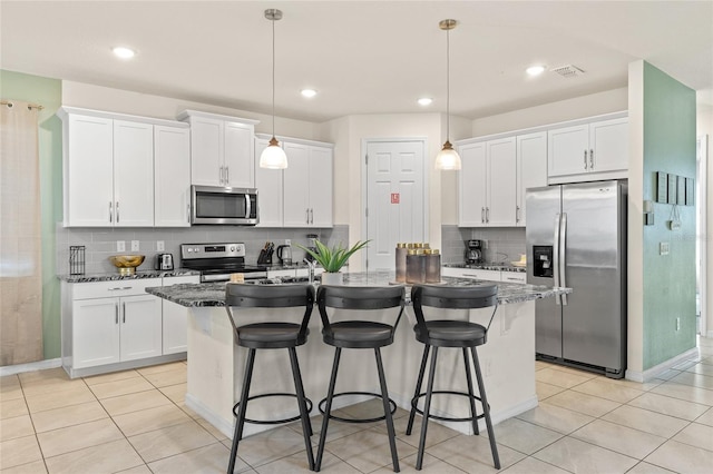 1809 Tropical Palms Cir, Kissimmee, FL 34747 - kitchen featuring stainless steel appliances, an island with sink, a kitchen bar, decorative backsplash, and white cabinetry