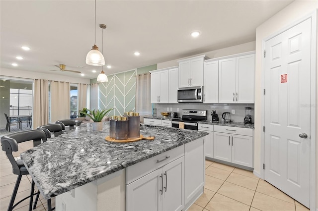 1809 Tropical Palms Cir, Kissimmee, FL 34747 - kitchen featuring appliances with stainless steel finishes, a breakfast bar area, white cabinets, light tile patterned floors, and recessed lighting