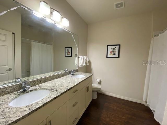 5370 Diplomat Ct Unit 107, Kissimmee, FL 34746 - full bathroom with toilet, double vanity, wood finished floors, baseboards, and curtained shower