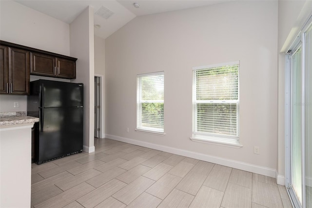 1206 Beechdale Ct, Deltona, FL 32725 - kitchen featuring freestanding refrigerator, dark brown cabinetry, baseboards, high vaulted ceiling, and light wood-style flooring