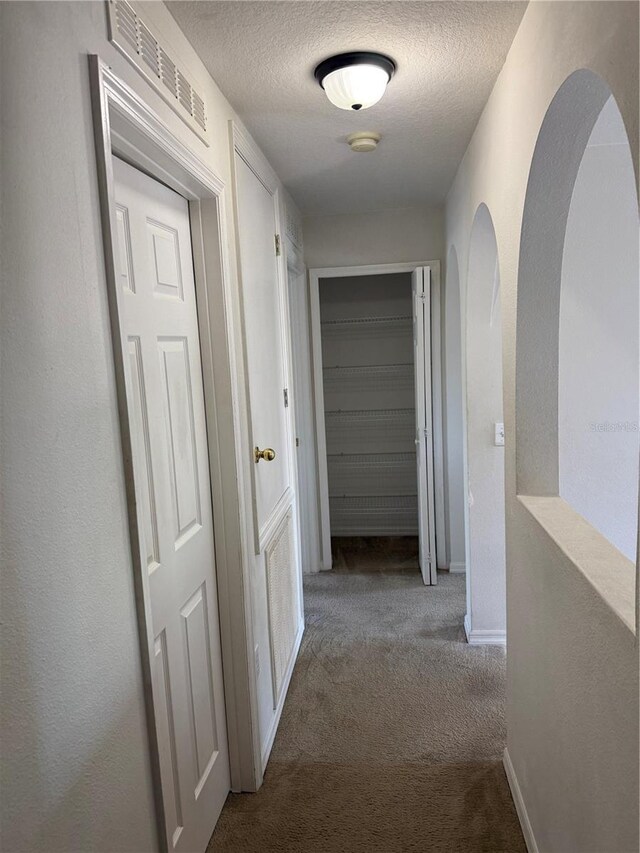 436 Hammerstone Ave, Haines City, FL 33844 - corridor with carpet flooring, a textured ceiling, arched walkways, and baseboards