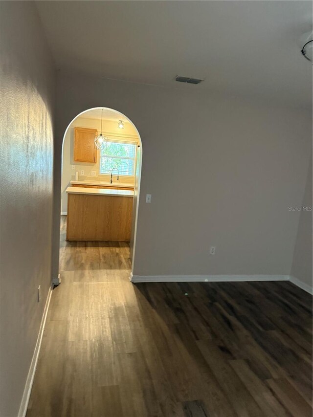 436 Hammerstone Ave, Haines City, FL 33844 - empty room featuring arched walkways, dark wood-style floors, and baseboards