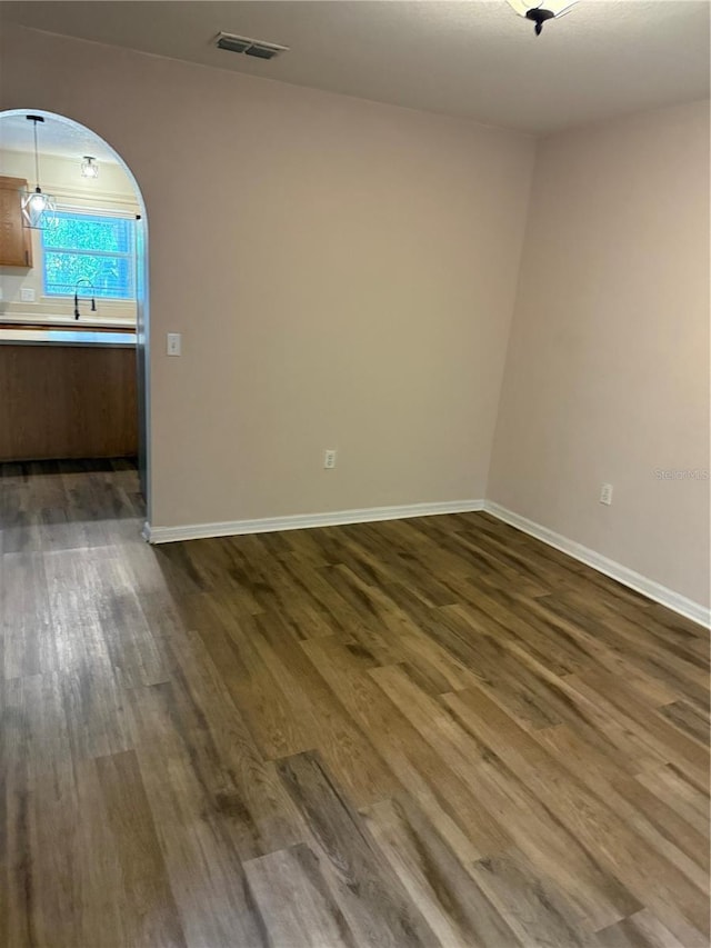 436 Hammerstone Ave, Haines City, FL 33844 - spare room with dark wood-style floors, arched walkways, and baseboards