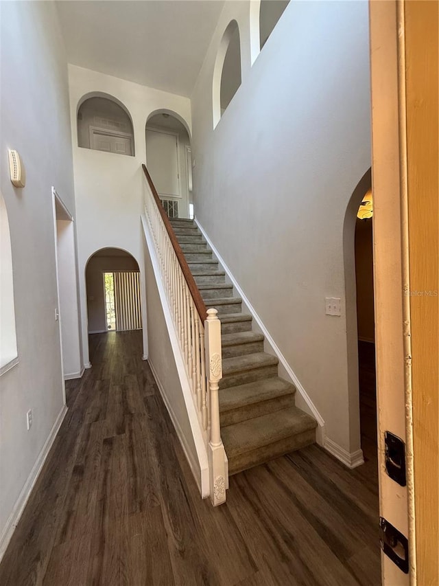 436 Hammerstone Ave, Haines City, FL 33844 - staircase with wood finished floors, arched walkways, baseboards, and a high ceiling