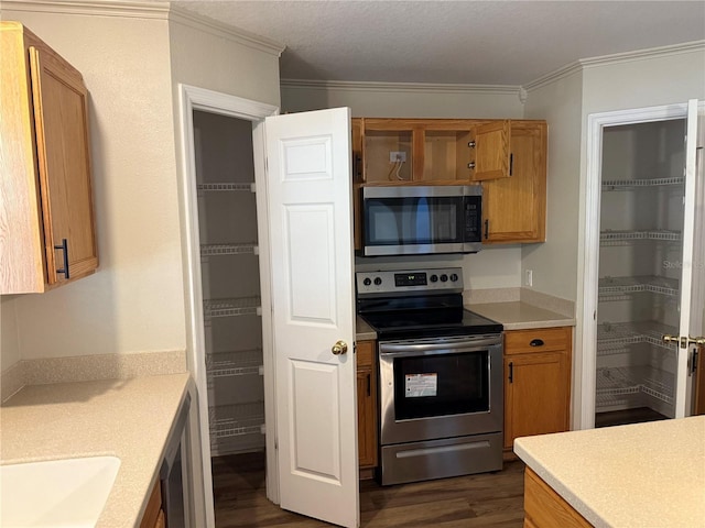 436 Hammerstone Ave, Haines City, FL 33844 - kitchen with appliances with stainless steel finishes, dark wood finished floors, light countertops, crown molding, and brown cabinets