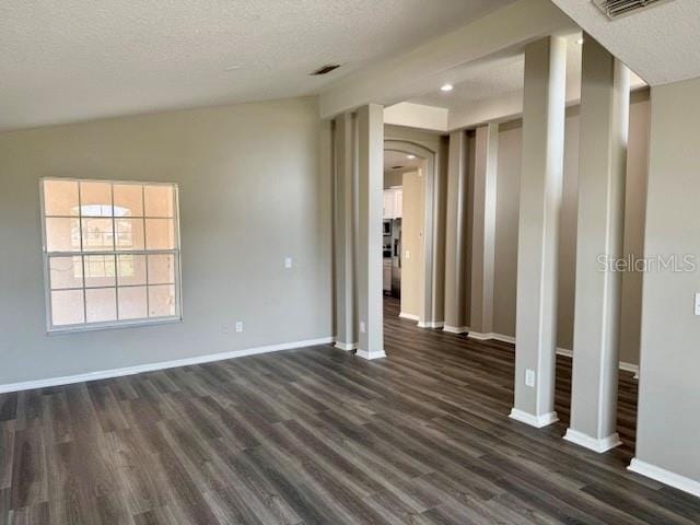 307 Dalton Ct, Davenport, FL 33897 - spare room featuring dark wood-style floors, baseboards, a textured ceiling, lofted ceiling, and arched walkways