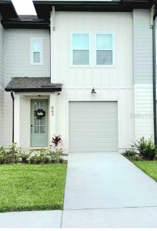 665 Longboat Dr, Davenport, FL 33896 - view of front facade featuring board and batten siding, driveway, a front yard, and an attached garage