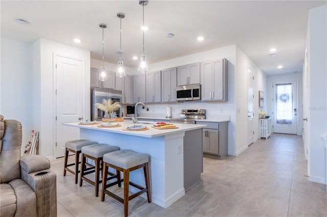 665 Longboat Dr, Davenport, FL 33896 - kitchen with appliances with stainless steel finishes, gray cabinetry, a sink, a breakfast bar, and light countertops