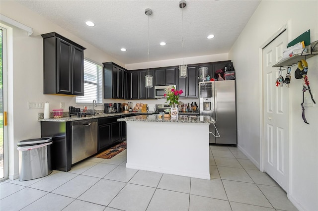 978 E 10th St, Apopka, FL 32703 - kitchen featuring stainless steel appliances, light stone counters, a textured ceiling, decorative light fixtures, and a sink