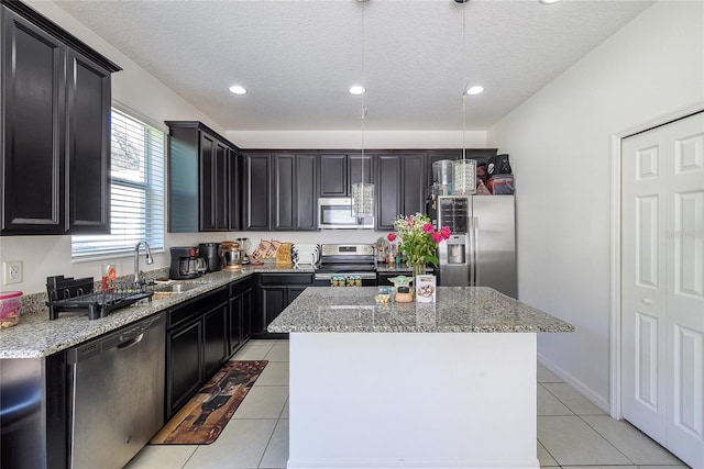 978 E 10th St, Apopka, FL 32703 - kitchen with appliances with stainless steel finishes, a sink, light stone countertops, a center island, and light tile patterned floors
