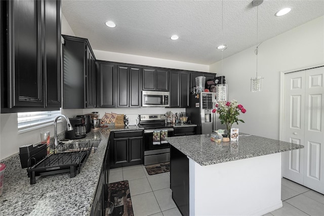 978 E 10th St, Apopka, FL 32703 - kitchen featuring appliances with stainless steel finishes, dark cabinetry, stone countertops, a sink, and a kitchen island
