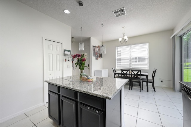 978 E 10th St, Apopka, FL 32703 - kitchen featuring dark cabinetry, light tile patterned floors, a chandelier, a kitchen island, and decorative light fixtures