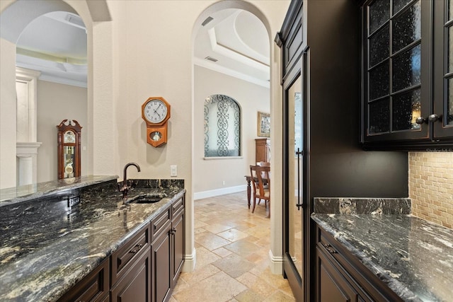 9253 Tibet Pointe Cir, Windermere, FL 34786 - indoor wet bar featuring a tray ceiling, stone tile flooring, ornamental molding, baseboards, and arched walkways