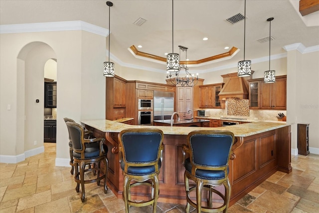 9253 Tibet Pointe Cir, Windermere, FL 34786 - kitchen featuring stone tile floors, built in fridge, brown cabinets, light stone countertops, and crown molding