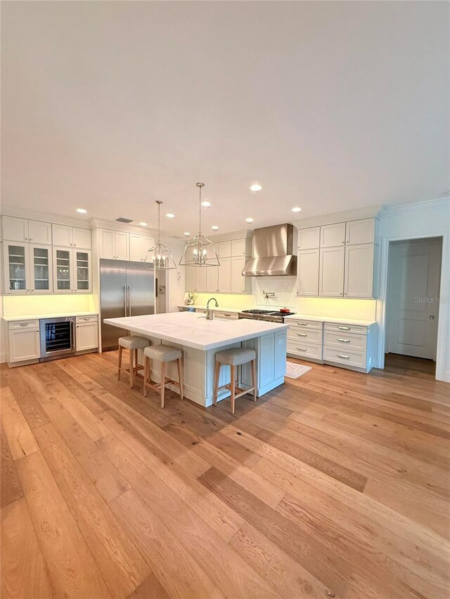 4309 W Beachway Dr, Tampa, FL 33609 - kitchen featuring stainless steel appliances, wall chimney range hood, wine cooler, light wood-style flooring, and recessed lighting