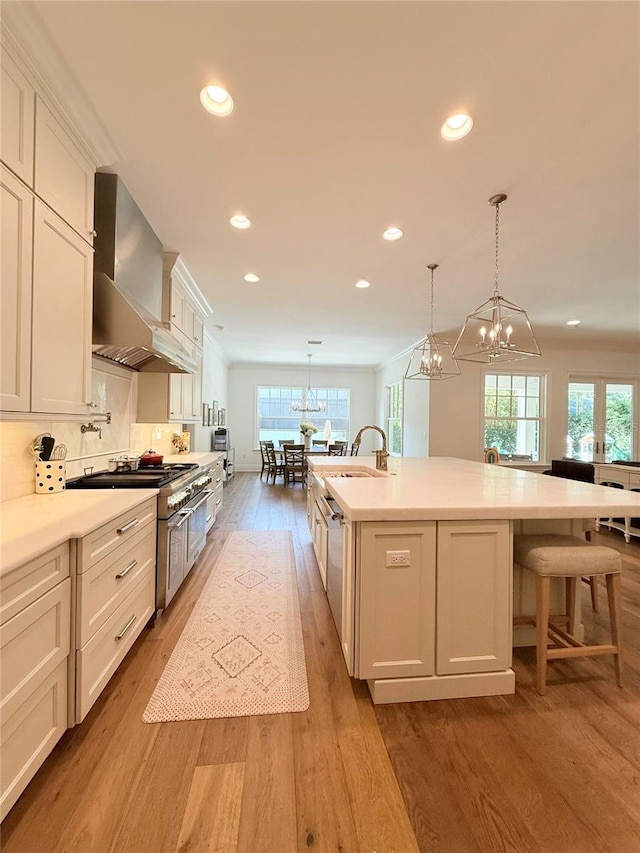 4309 W Beachway Dr, Tampa, FL 33609 - kitchen with wall chimney exhaust hood, a chandelier, light wood-type flooring, light countertops, and recessed lighting