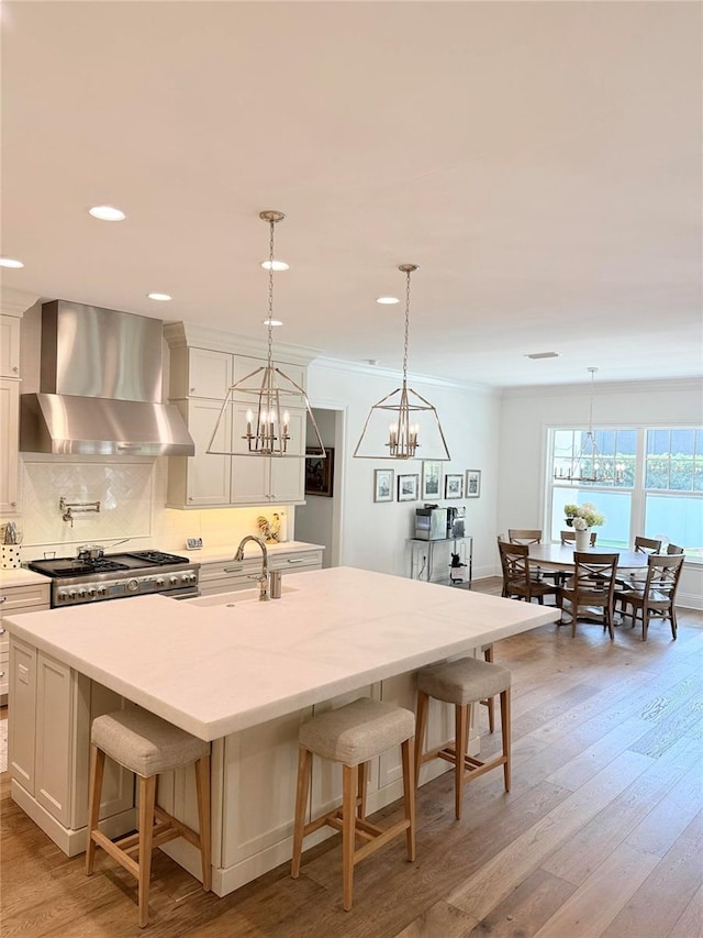 4309 W Beachway Dr, Tampa, FL 33609 - kitchen featuring wall chimney exhaust hood, a sink, a chandelier, tasteful backsplash, and a kitchen bar