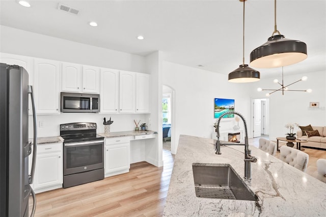 1932 Reed Hill Dr, Windermere, FL 34786 - kitchen featuring appliances with stainless steel finishes, a sink, arched walkways, light wood finished floors, and light stone counters