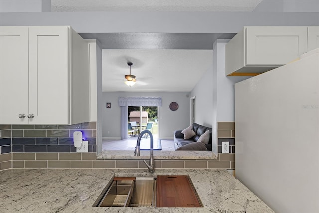 891 Licaria Dr, Ocoee, FL 34761 - kitchen featuring freestanding refrigerator, white cabinets, light stone counters, open floor plan, and a textured ceiling