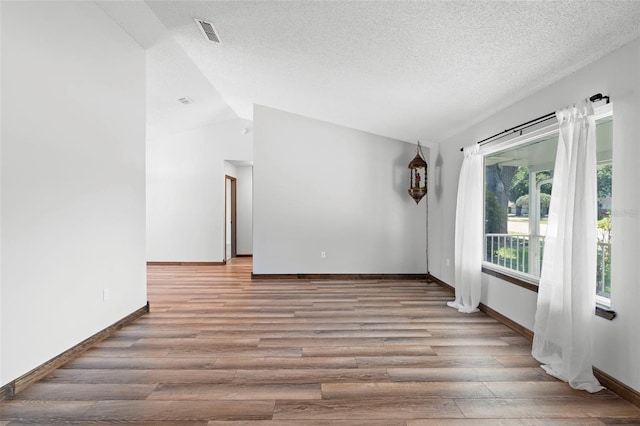 6906 Sawmill Blvd, Ocoee, FL 34761 - spare room featuring wood finished floors, baseboards, vaulted ceiling, and a textured ceiling