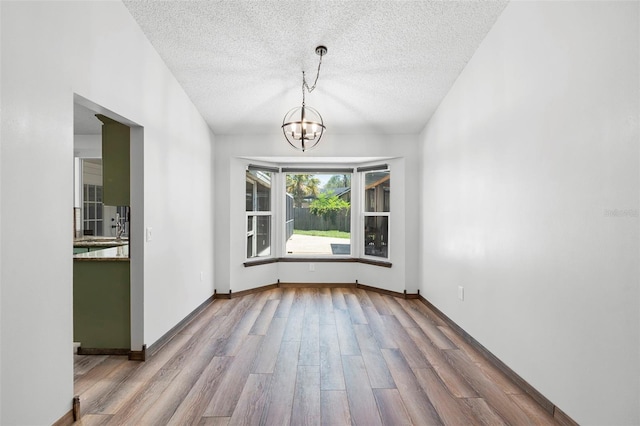 6906 Sawmill Blvd, Ocoee, FL 34761 - unfurnished dining area with wood finished floors, a textured ceiling, a chandelier, and baseboards