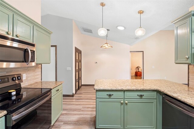 6906 Sawmill Blvd, Ocoee, FL 34761 - kitchen featuring appliances with stainless steel finishes, vaulted ceiling, light wood finished floors, hanging light fixtures, and a peninsula